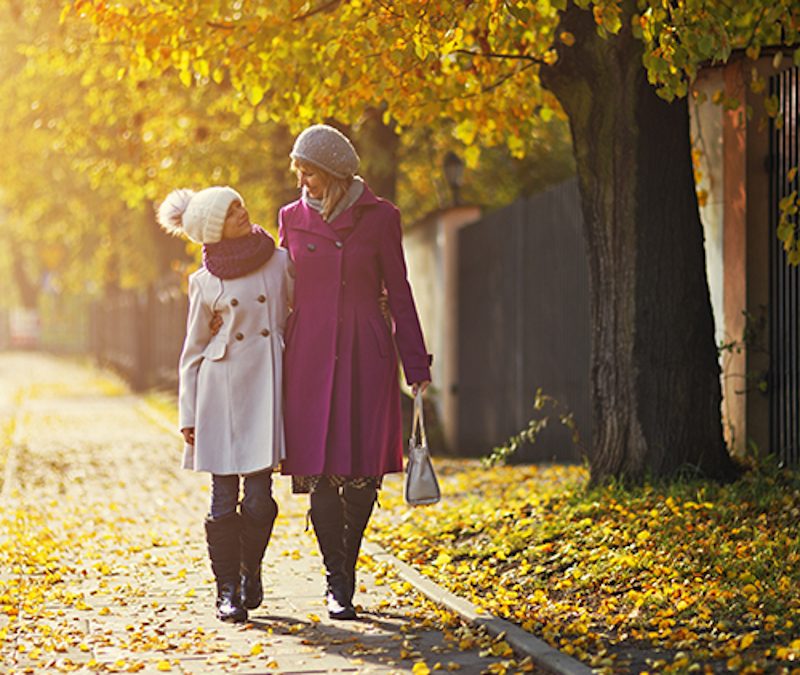two people hand in hand walking with trees in the background